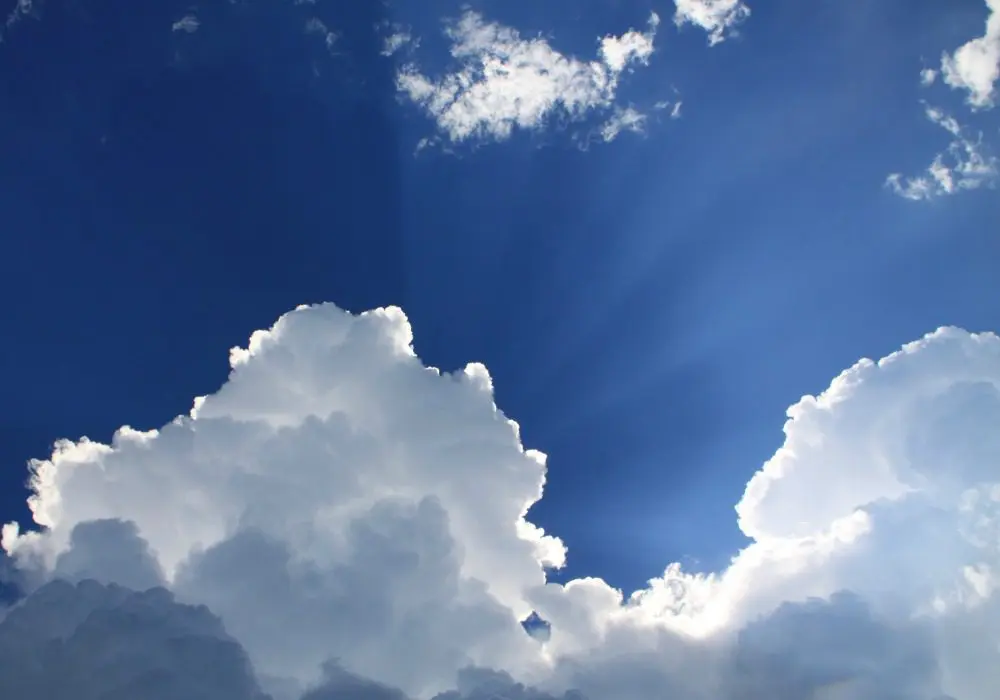 A blue sky with some clouds and sun shining through